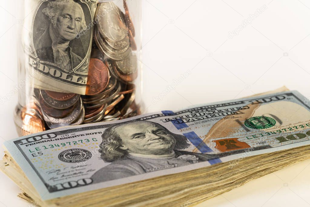 Glass jar and pile of money isolated on a white background.