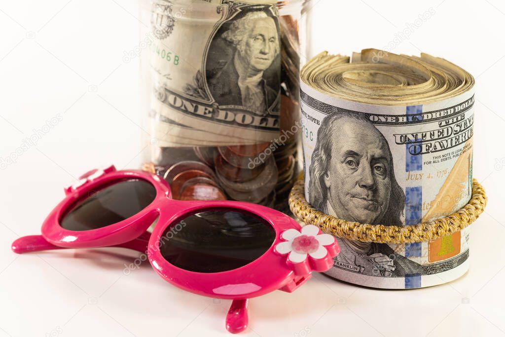 Glass jar with money, kids sunglasses, and roll of money isolated on a white background.