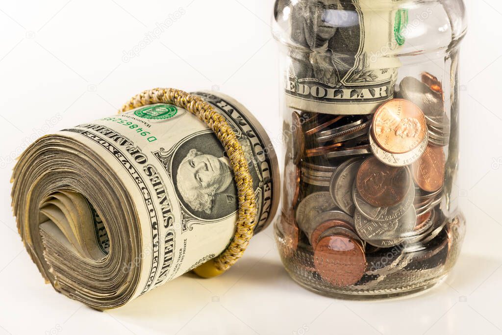 Glass jar and roll of money isolated on a white background.