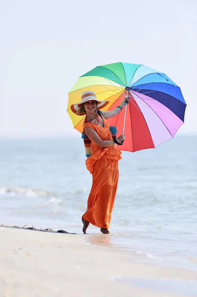Mulher segurando guarda-chuva na praia no verão — Fotografia de Stock