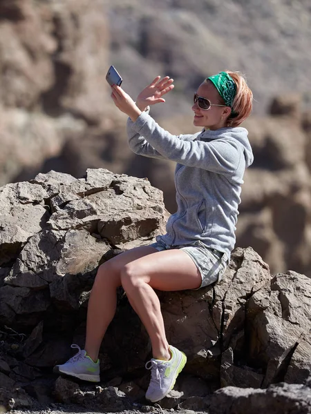 Kvinnlig resenär tar selfie på steniga bakgrunden — Stockfoto