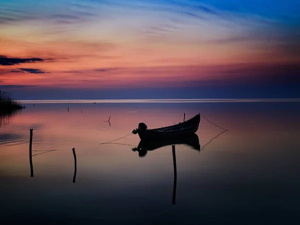 Nascer do sol sobre a água e silhueta do barco de pesca — Fotografia de Stock