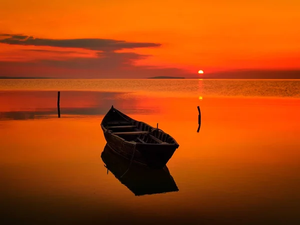 Pôr do sol sobre a água e silhueta do barco de pesca — Fotografia de Stock