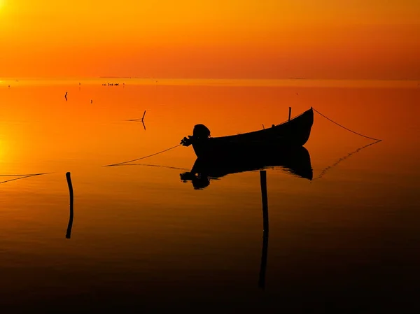 Pôr do sol sobre a água e silhueta do barco de pesca — Fotografia de Stock