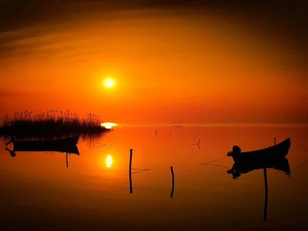 Pôr do sol sobre a água e silhueta do barco de pesca — Fotografia de Stock