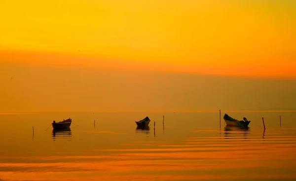 Закат над водой и силуэт рыбацких лодок — стоковое фото