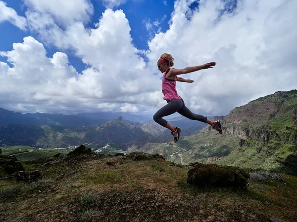 Mujer saltando en la cima de la montaña — Foto de Stock