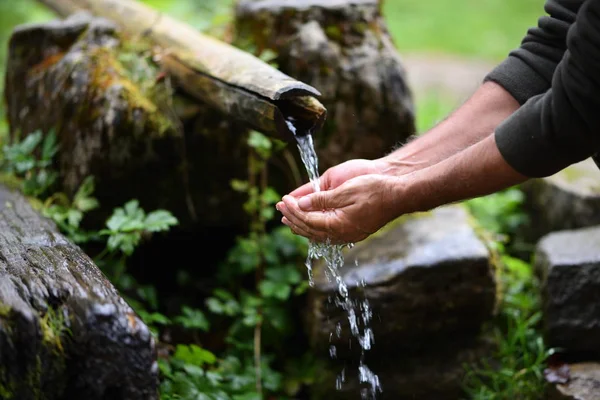 Uomo che lava le mani in acqua fresca, fredda e potabile di montagna spri — Foto Stock