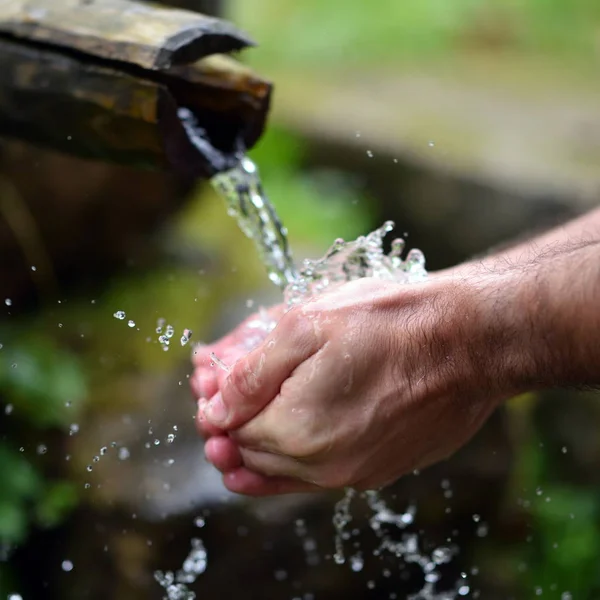 Homem lavando as mãos em fresco, frio, água potável de montanha spri — Fotografia de Stock