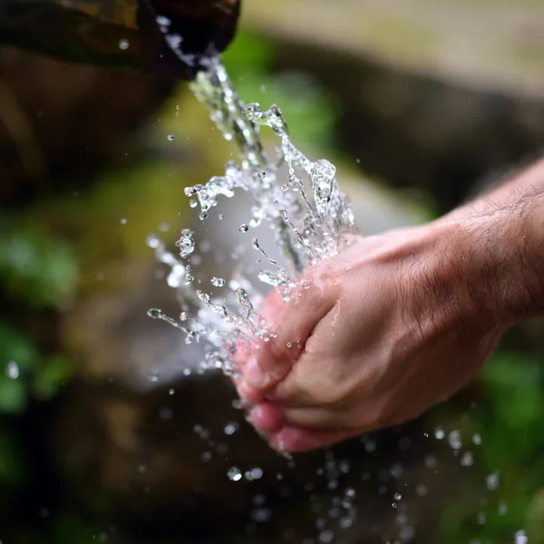 Uomo che lava le mani in acqua fresca, fredda e potabile di montagna spri — Foto Stock