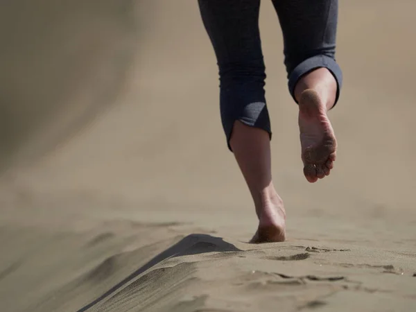 Bara fötter av ung kvinna jogging/promenad på stranden i soluppgången — Stockfoto