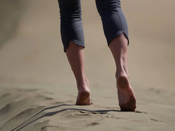 Bara fötter av ung kvinna jogging/promenad på stranden i soluppgången — Stockfoto