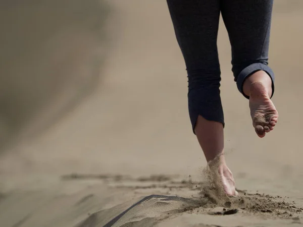 Bara fötter av ung kvinna jogging/promenad på stranden i soluppgången — Stockfoto