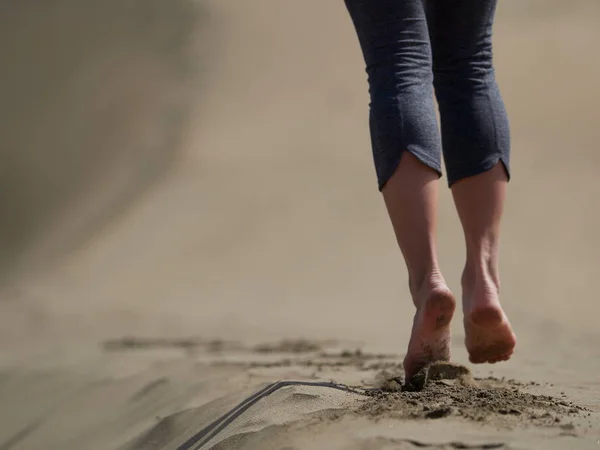 Bare feet of young woman jogging/walking on the beach at sunrise — Stock Photo, Image