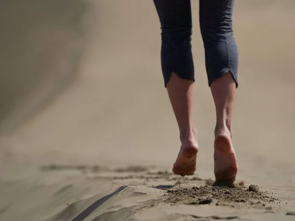 Barfüßige junge Frau joggt / geht bei Sonnenaufgang am Strand — Stockfoto