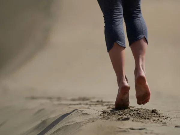 Bara fötter av ung kvinna jogging/promenad på stranden i soluppgången — Stockfoto