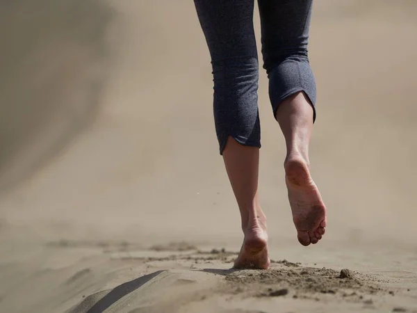 Bara fötter av ung kvinna jogging/promenad på stranden i soluppgången — Stockfoto