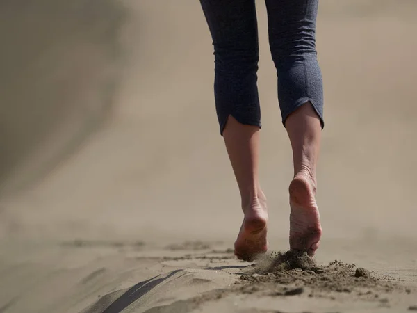 Bara fötter av ung kvinna jogging/promenad på stranden i soluppgången — Stockfoto