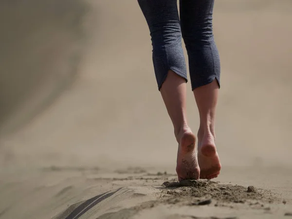 Голі ноги молодої жінки бігають/ ходять на пляжі на сході сонця — стокове фото