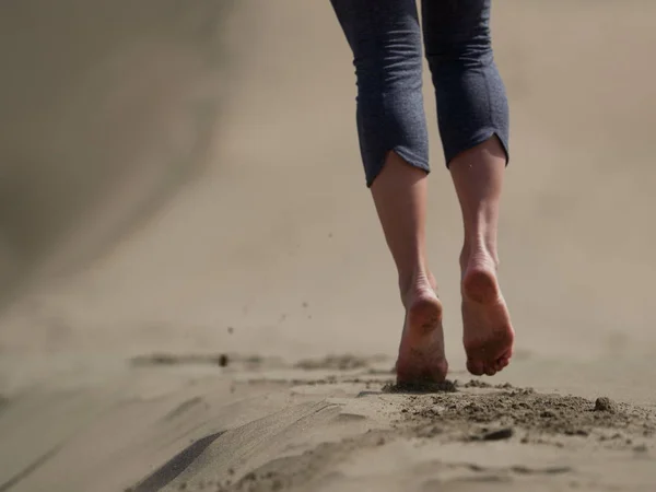 Blote voeten van jonge vrouw joggen/wandelen op het strand bij zonsopgang — Stockfoto