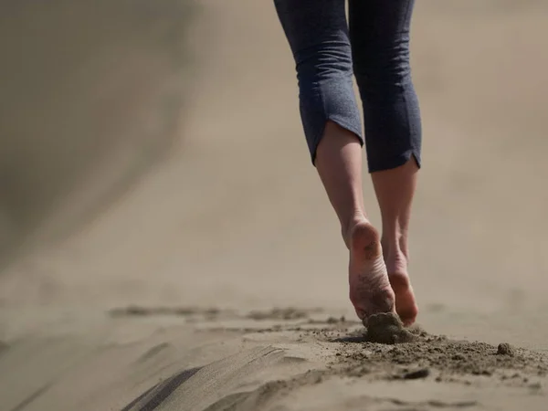 Bara fötter av ung kvinna jogging/promenad på stranden i soluppgången — Stockfoto