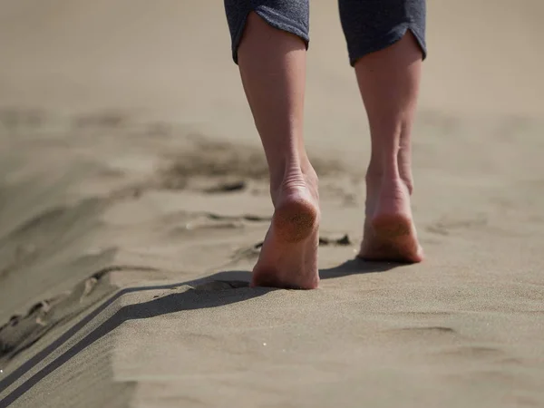 Blote voeten van jonge vrouw joggen/wandelen op het strand bij zonsopgang — Stockfoto