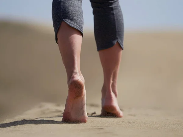 Bara fötter av ung kvinna jogging/promenad på stranden i soluppgången — Stockfoto