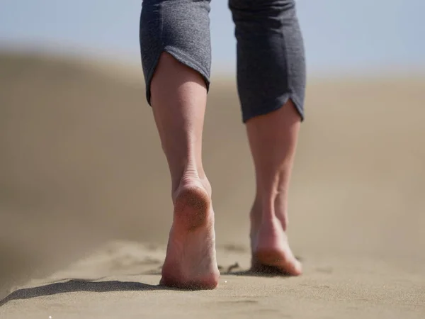 Bara fötter av ung kvinna jogging/promenad på stranden i soluppgången — Stockfoto