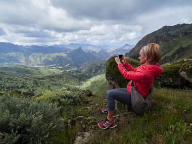 Cliff'in kenar ve çekici fotoğraflar üzerinde oturan kadın turist