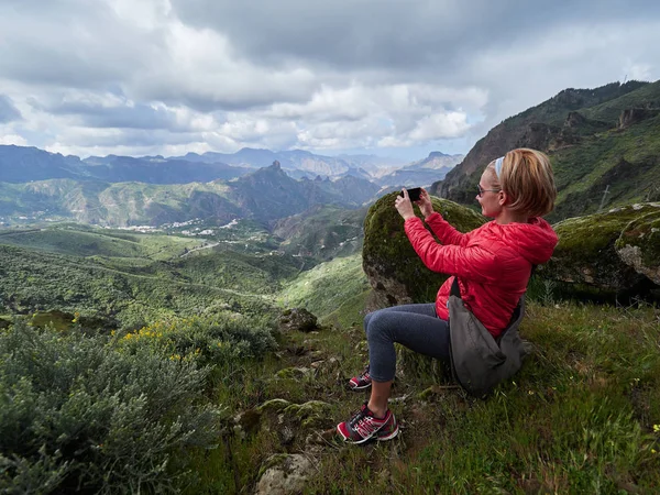 Touristin sitzt auf Klippe und fotografiert — Stockfoto