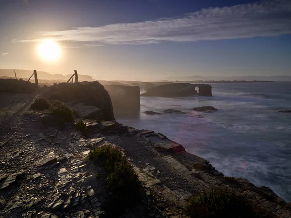 Hermosa puesta de sol y arcos de piedra en Playa de las Catedrales dur —  Fotos de Stock