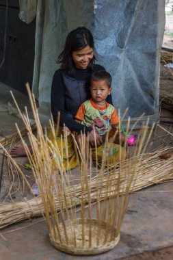 Mother and child sitting in their Cambodian village clipart