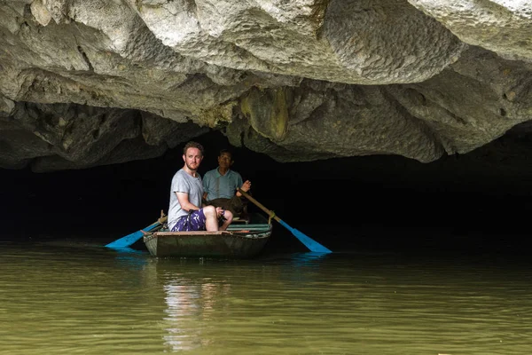 Un turista y guía salen de una cueva inundada en Trang An UNESCO World —  Fotos de Stock