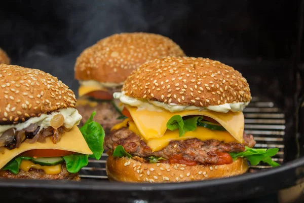 Cheeseburgers caseiros com tomate, pepino, alface cozida em grelha e carvão — Fotografia de Stock