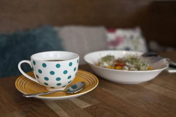 Gestippelde kopje thee en kom met salade — Stockfoto