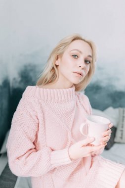 Sevimli kız okuma bir kitap, konfor ve yenilikçi kavramı ile çay, rahat bir sandalye üzerinde