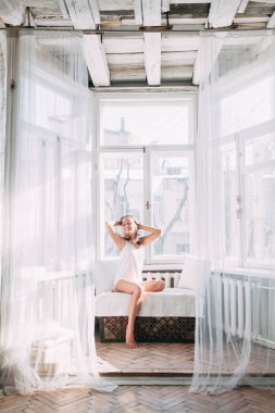 Modern güneşli daire sabahları yatakta oldukça genç kız portresi. Yudumlarken ve gülümseyen, kahve içme ve yerde yatarken