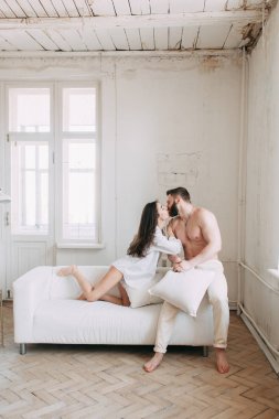 Genç mutlu çift evde, sarılma ve öpüşme vardır. Sevilen olanlar pijama deli ve gülmek güzel güneşli sabah.