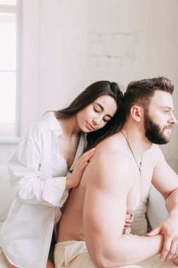 Genç mutlu çift evde, sarılma ve öpüşme vardır. Sevilen olanlar pijama deli ve gülmek güzel güneşli sabah.