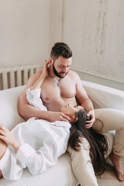 Genç mutlu çift evde, sarılma ve öpüşme vardır. Sevilen olanlar pijama deli ve gülmek güzel güneşli sabah.