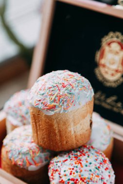 Bahar Easter Pasta krema şeker, sprinkles ve kuru üzüm ile hamur mayaları, yapılmış. Dekor ve saman, ahşap arka plan üzerinde çevrili