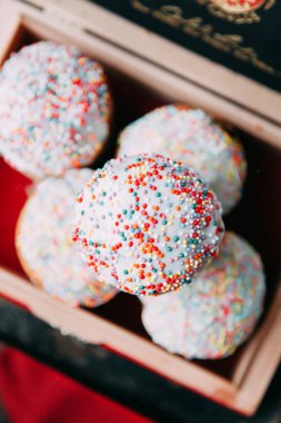 Bahar Easter Pasta krema şeker, sprinkles ve kuru üzüm ile hamur mayaları, yapılmış. Dekor ve saman, ahşap arka plan üzerinde çevrili