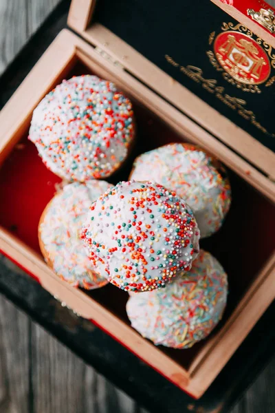 Bahar Easter Pasta krema şeker, sprinkles ve kuru üzüm ile hamur mayaları, yapılmış. Dekor ve saman, ahşap arka plan üzerinde çevrili