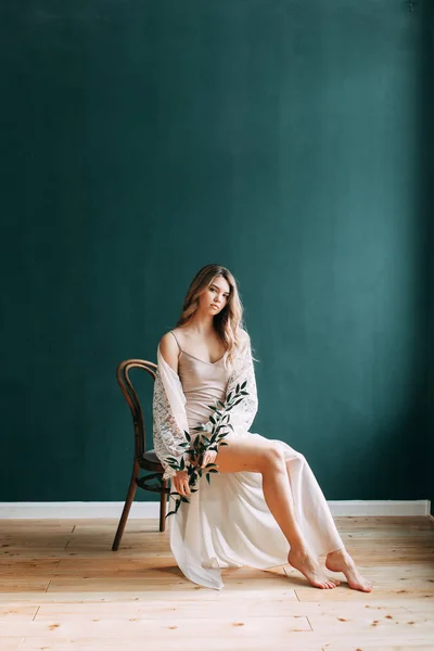 Young beautiful bride in boudoir and wedding dress, with a wreath and a bouquet in her hands. London wedding trends, stylish photoshoot