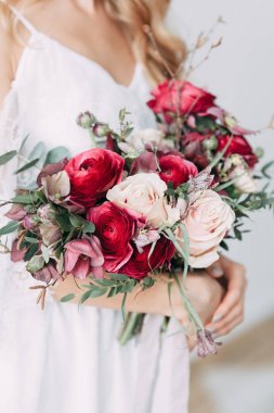 Hafif bir düğün gelinin elbise kırmızı çiçekler, İskandinav tarzı hafif bir duvara bir buket. Avrupa düğün, çağdaş eğilimler ve ilham