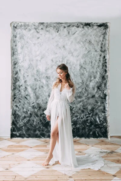 Beautiful young bride in boudoir dress on canvas background with paint. Wedding trends and ideas 2018, spring inspiration. Wedding in the Studio