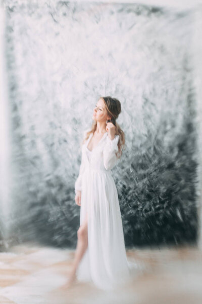 Beautiful young bride in boudoir dress on canvas background with paint. Wedding trends and ideas 2018, spring inspiration. Wedding in the Studio