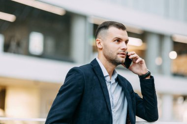 Konuşmalar, telefon görüşmeleri, görüşmeler. Ofiste başarılı genç bir adamın portresi.. 