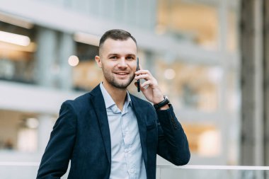 Konuşmalar, telefon görüşmeleri, görüşmeler. Ofiste başarılı genç bir adamın portresi.. 