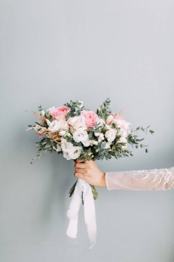 Okaliptüs ve Ranunculus çiçekleri ellerinde. Gelinin buketi parlak stüdyoda.. 